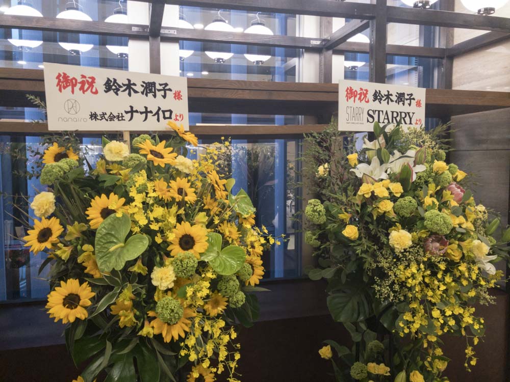 2器の2段スタンドに飾られた黄色いヒマワリやバラの花の写真